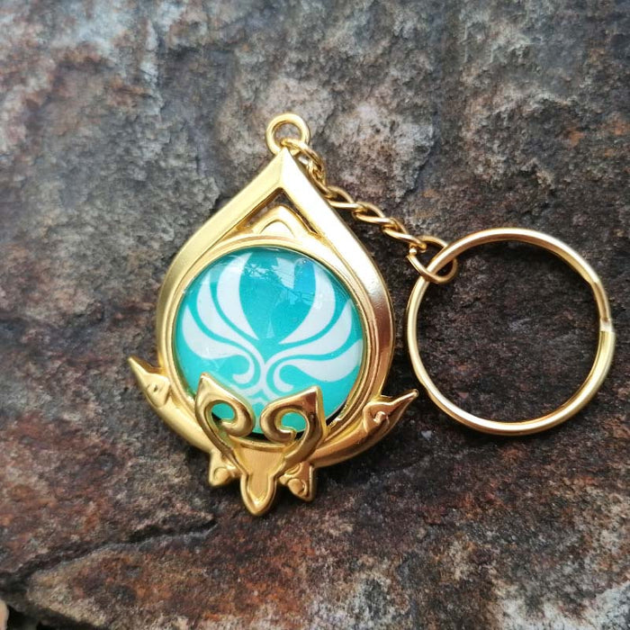 Genshin Impact Sumeru Vision Keychain: gold, turquoise stylized octopus-like emblem, fantasy emblem style