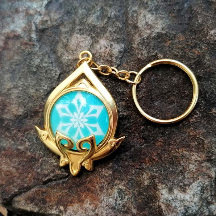 Genshin Impact Sumeru Vision Keychain: gold, turquoise stylized octopus-like emblem, fantasy emblem style