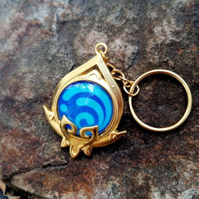 Genshin Impact Sumeru Vision Keychain: gold, turquoise stylized octopus-like emblem, fantasy emblem style