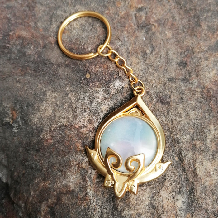 Genshin Impact Sumeru Vision Keychain: gold, turquoise stylized octopus-like emblem, fantasy emblem style
