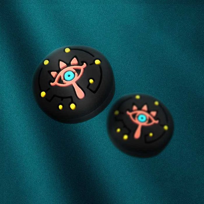 Zelda Switch Thumb Grips with Sheikah Slate: black, pink stylized eye symbol, cartoon style